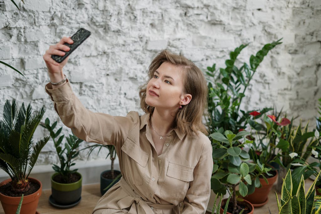 Photo of Woman Taking Selfie Using Smartphone Near Potted Plants